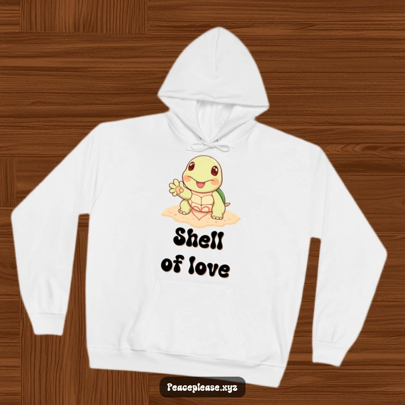Funny hoodie with a cheerful turtle paw drawing a heart symbol in the sand, perfect for expressing love by the sea.